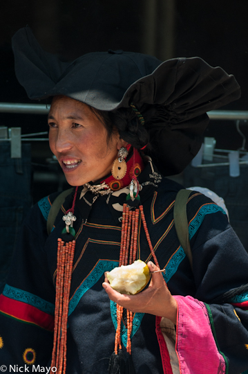 A Suo Di Yi woman from the village of Bapu eating an apple while on a visit to Niuniuba in Daliangshan.