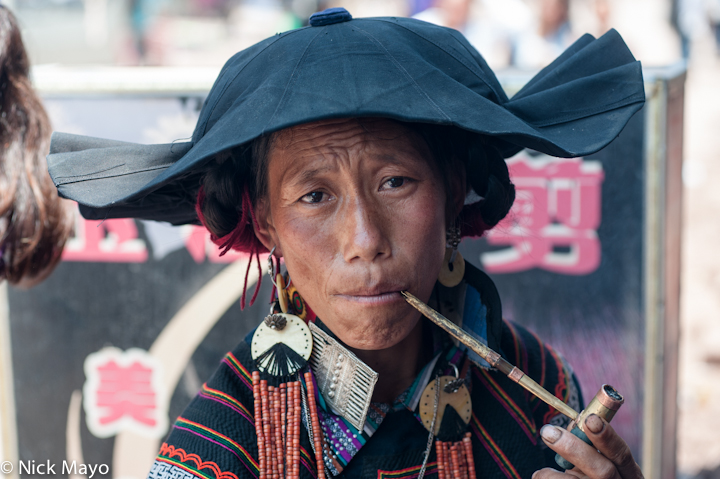 A Suo Di Yi woman from the village of Bapu smoking a pipe while on a visit to Niuniuba in Daliangshan.