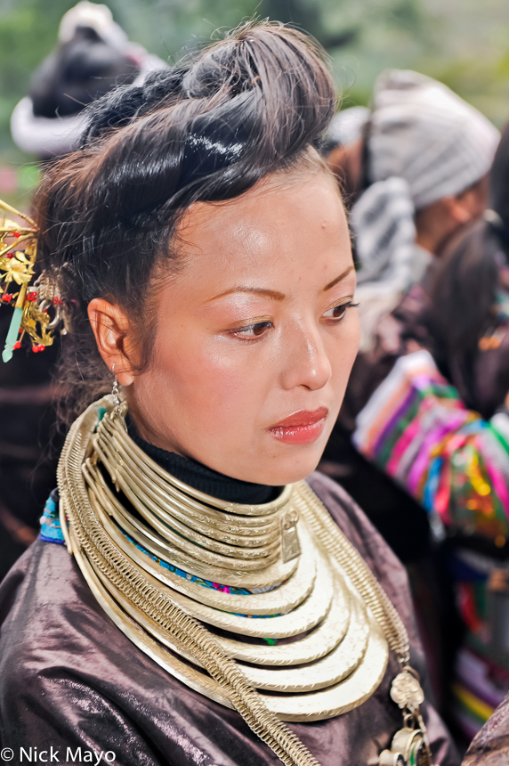 A Dong lady with a traditional hairstyle and wearing many silver necklaces at a festival in Congjiang.