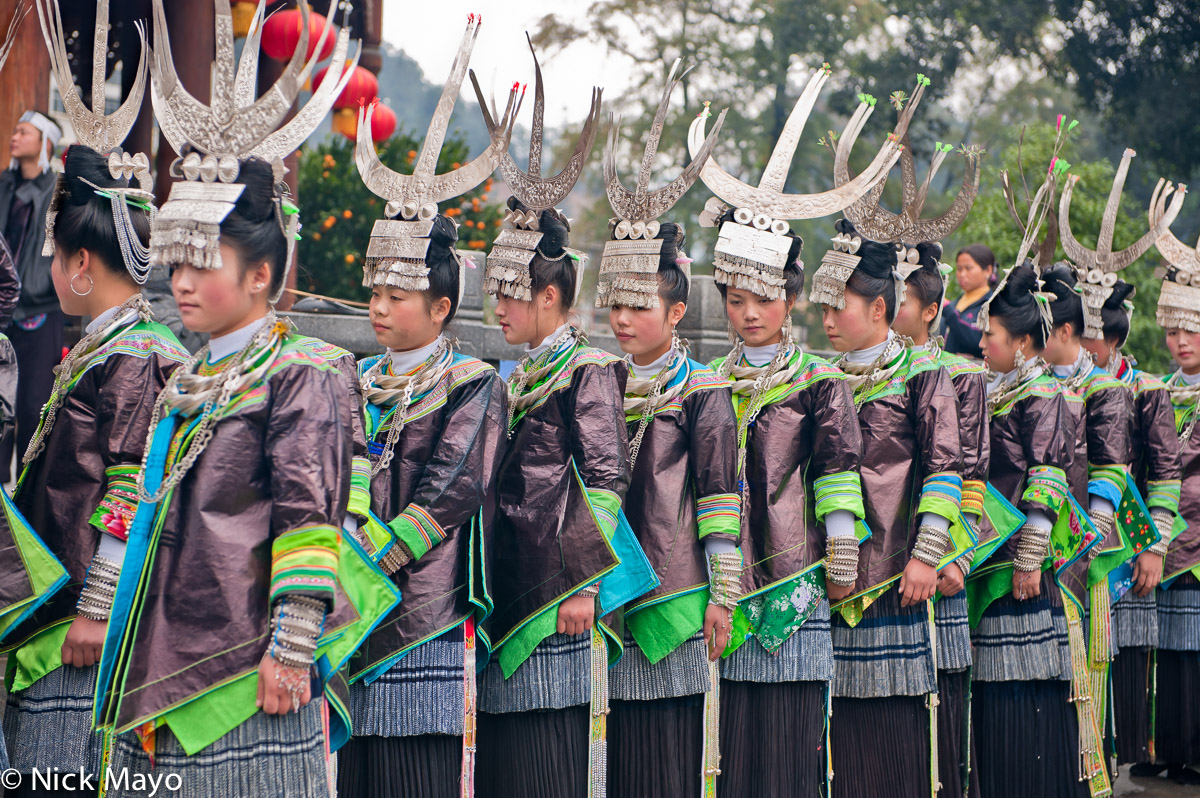 Miao girls, wearing festival clothes of "horn" shaped headdresses and heavy bracelets and necklaces, in Congjiang.