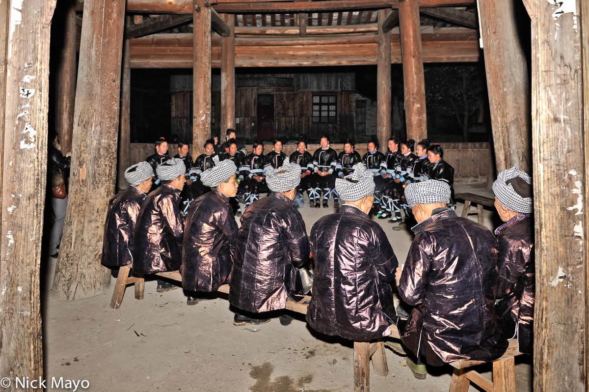 A male Da Ge Ensemble singing while seated in a drum tower at a Dong festival in Xioahuang.