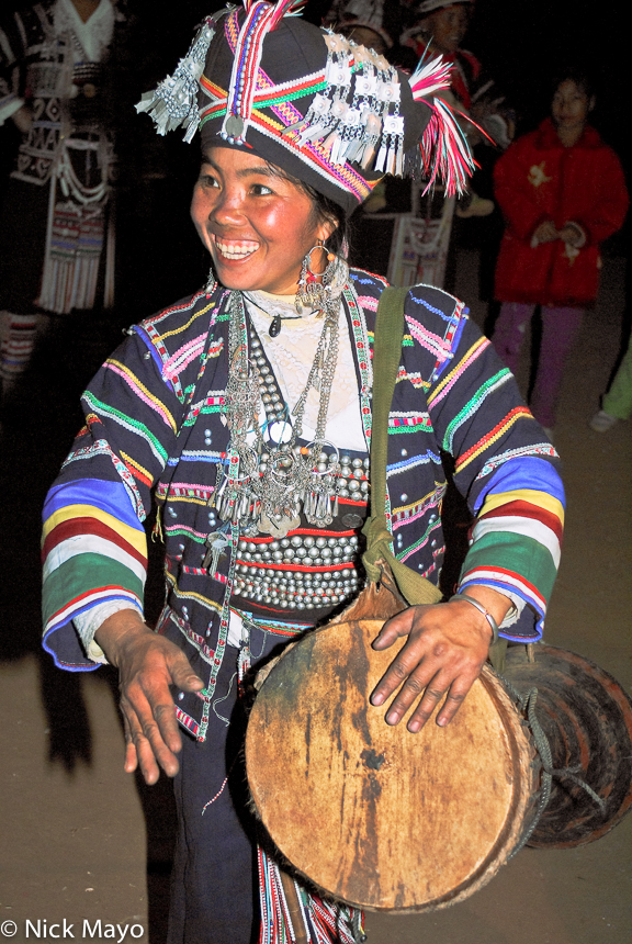 A smiling Pin Toh Aini (Hani) woman hand drumming on a frame drum at a New Year's day festival in Chung Tsai.