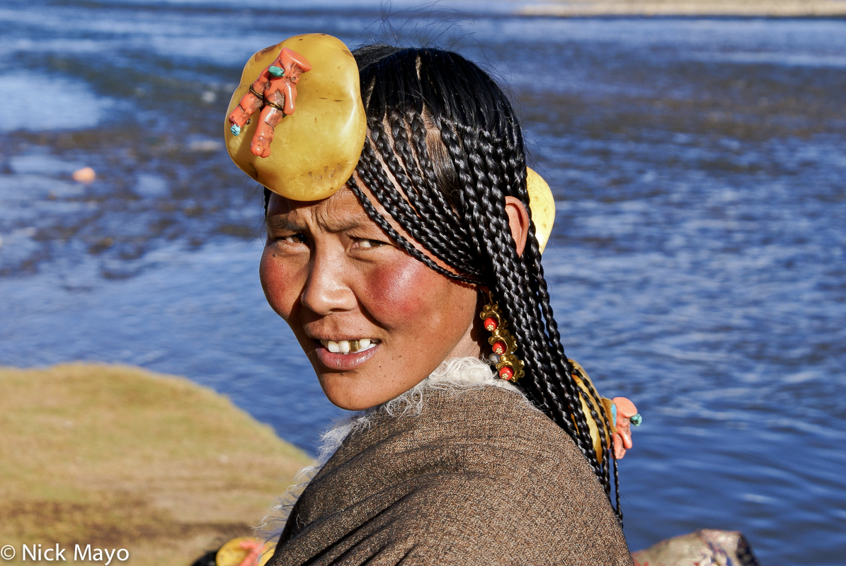 A Tibetan woman wearing an amber hair piece attending an assembly at the Sershul monastery.