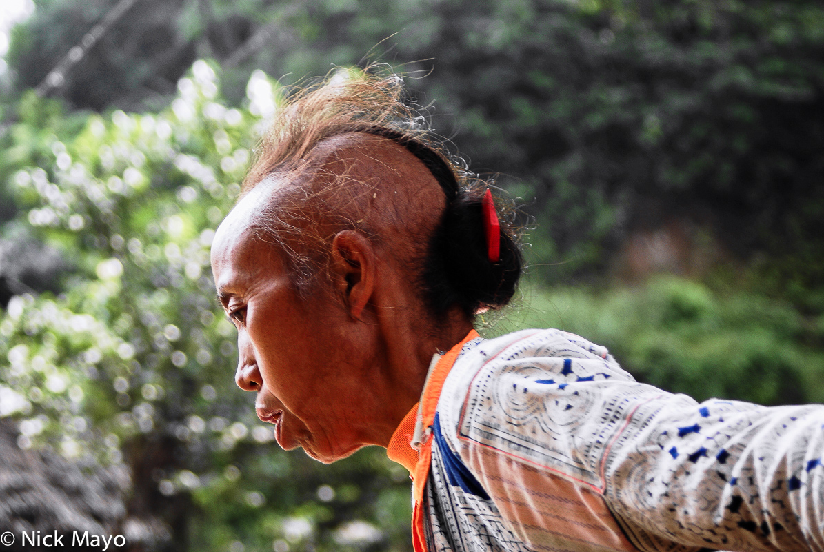 An older Qing Miao woman from Longee village with partially shaven hair.