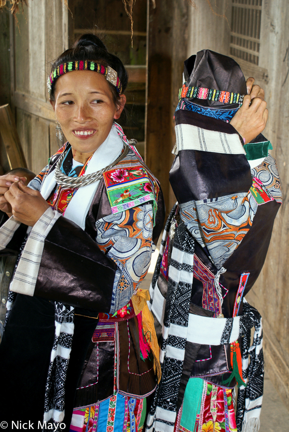 Women from the Miao village of Pai Shiao dressing in festival attire including a twisted silver necklace.