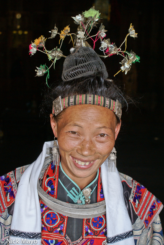 A woman from the Miao village of Pai Shiao dressed in festival attire including earrings, hair piece and necklace.