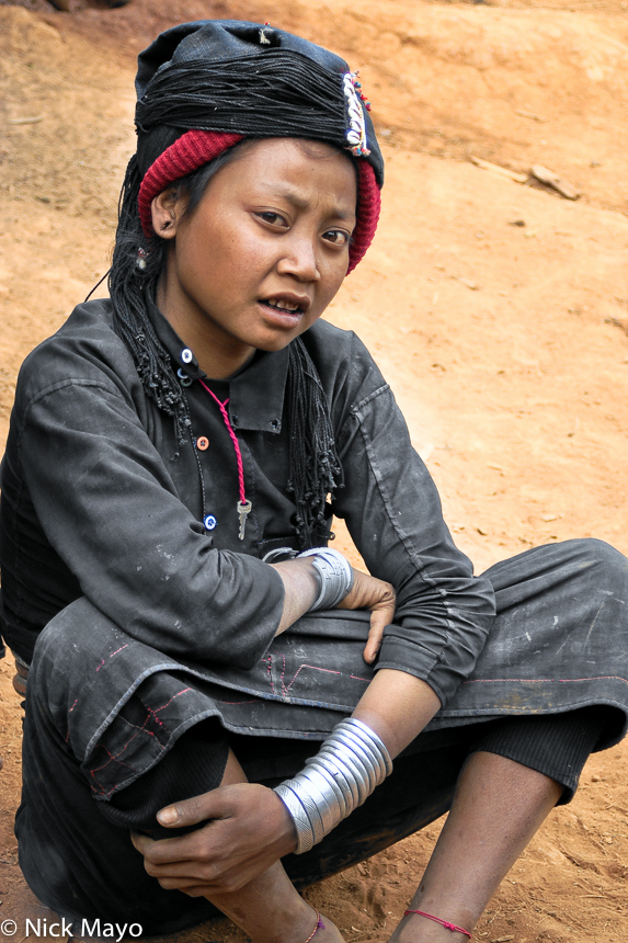 An Eng girl wearing traditional bracelets reposing in Ban Lu village.