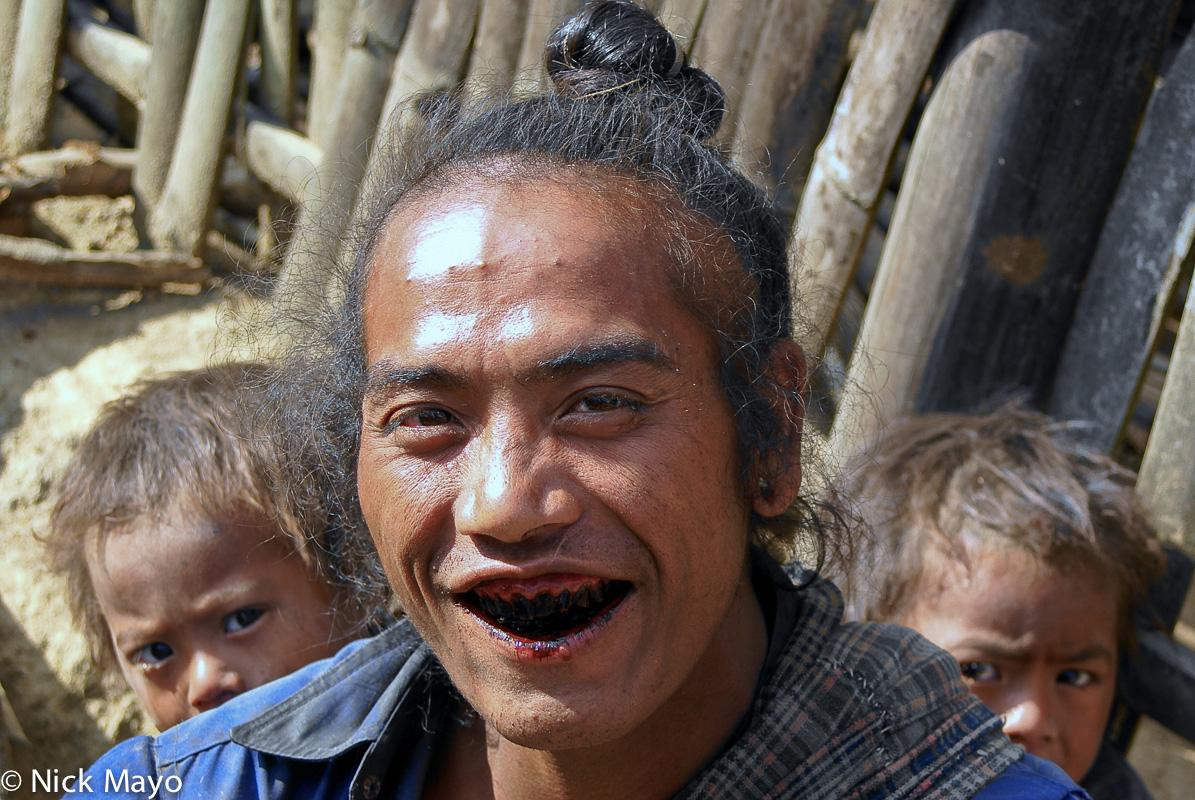 An Eng man in Ban Nong village with a traditional hair top knot displaying teeth blackened from chewing betel.