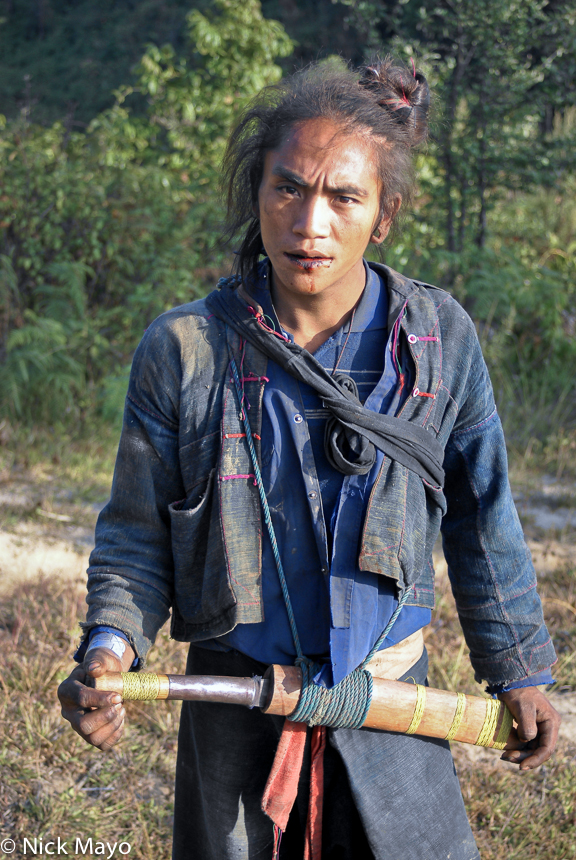 An Eng man with a traditional hair top knot and carrying a field knife near Ban Nong village.