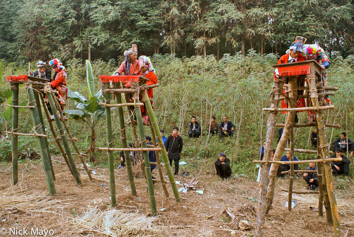 Initiates, accompanied by their fathers, readying themselves to ascend to the top of the jumping platforms used in the dujie...