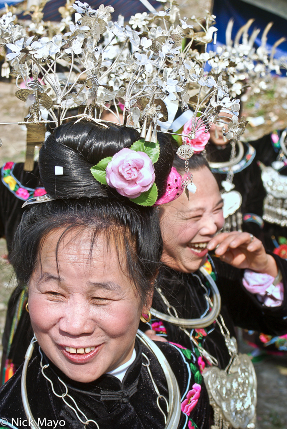 Miao woman wearing ornate silver hairpieces and heavy necklaces at a festival in Zhouxi.