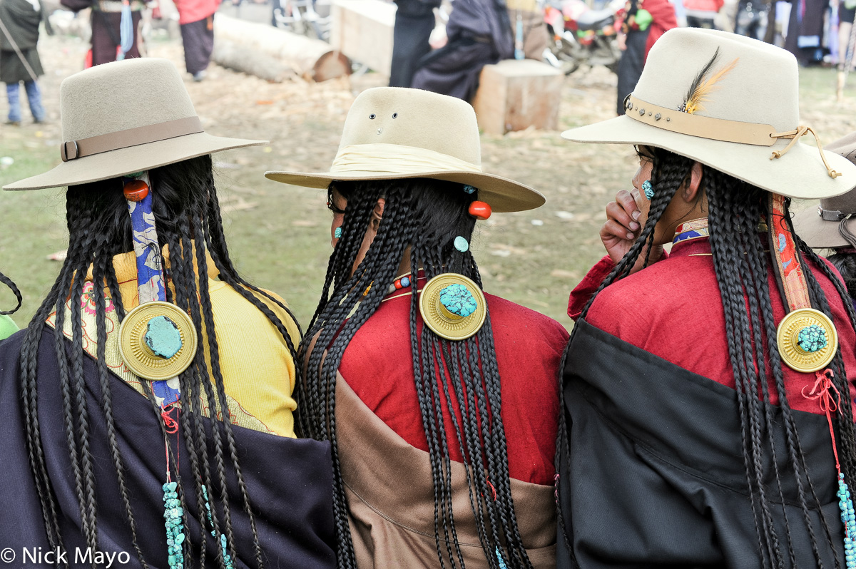 Three Tibetan women spectators wearing hair pieces featuring turquoise stones at a festival at the Yazer Gon monastery in Manigango...