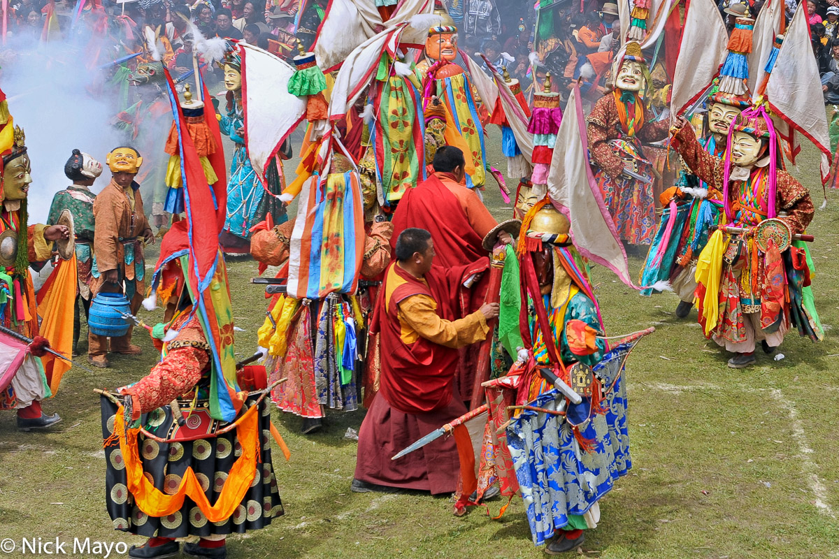 Masked monks wearing spectacular hats and carrying swords participating in the final dance at a festival at the Tibetan monastery...
