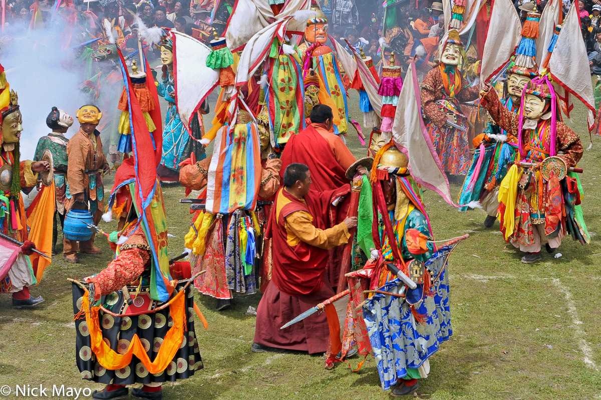 Masked monks wearing spectacular hats and carrying swords participating in the final dance at a festival at the Tibetan monastery...