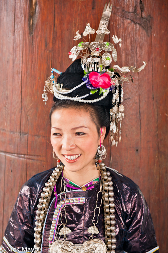 A Dong lady wearing an ornate hair piece, earrings and breastpiece at a festival in Congjiang.