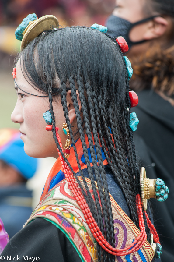 A Tibetan woman wearing decorative hair pieces at a festival in Manigango.