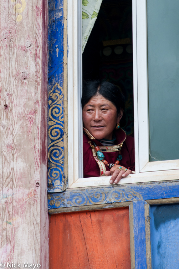 A Tibetan woman peering from a window during a festival at Manigango.