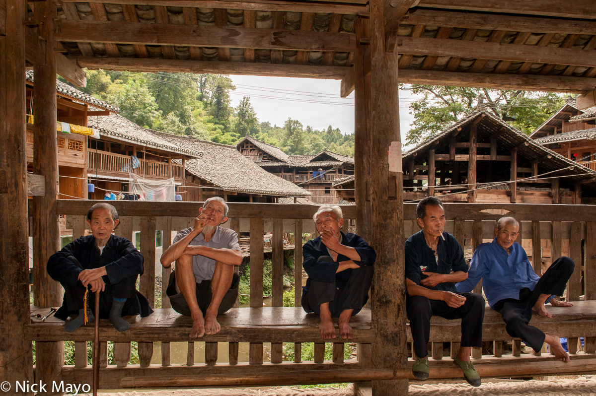 A group of Dong men relaxing on a Wind &amp; Rain bridge in the village of Da Li.