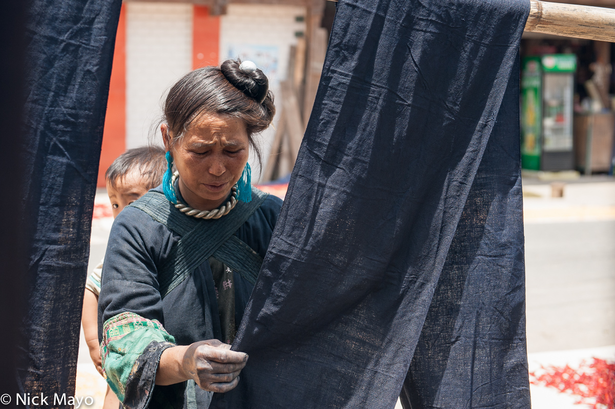 A Miao woman examining cloth drying in the village of Miao Peng.