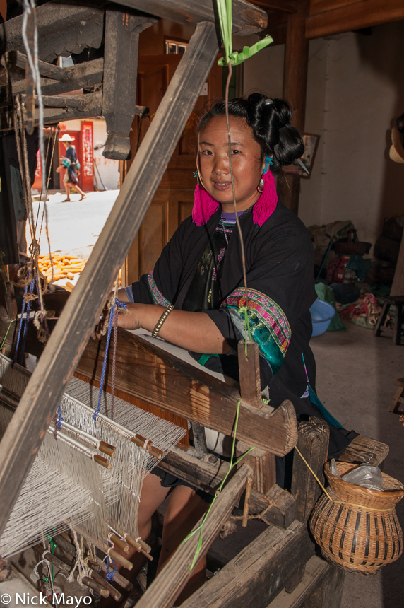 A Miao woman weaving on a frame loom in the village of Miao Peng.