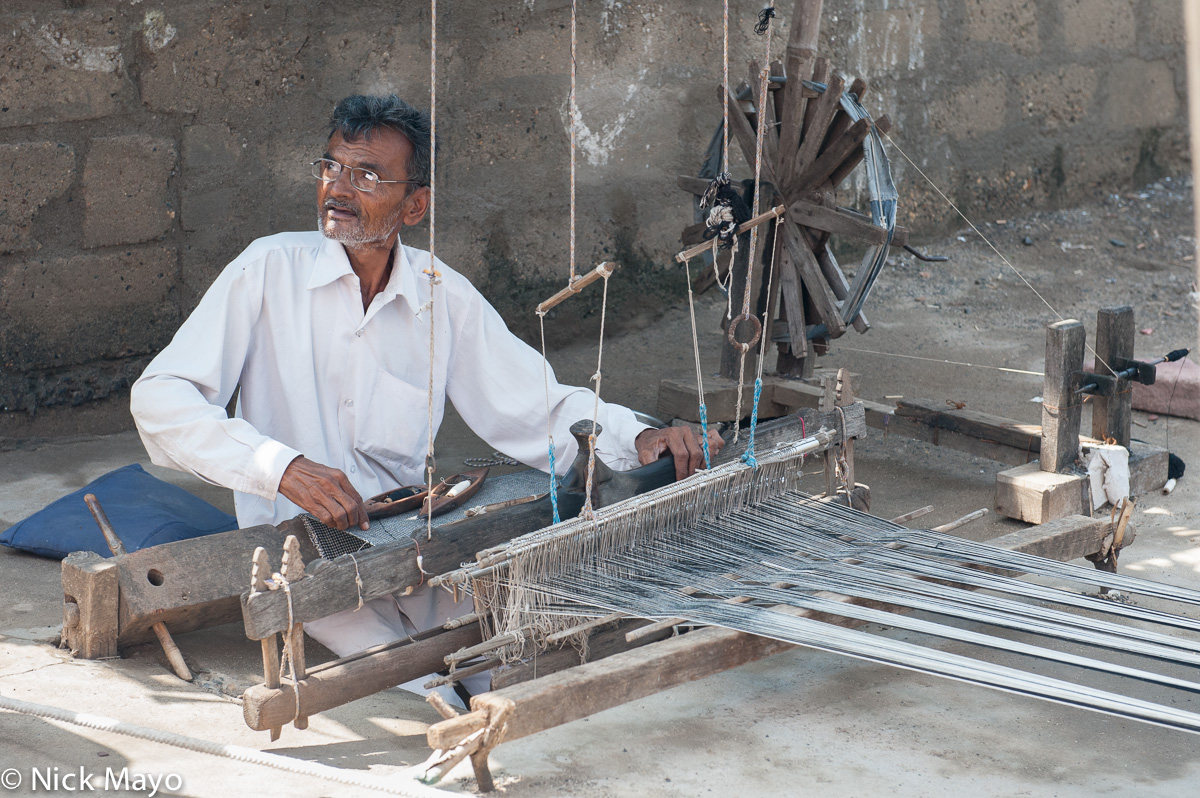 The tailor in the village of Midialo weaving on a foot treadle loom.