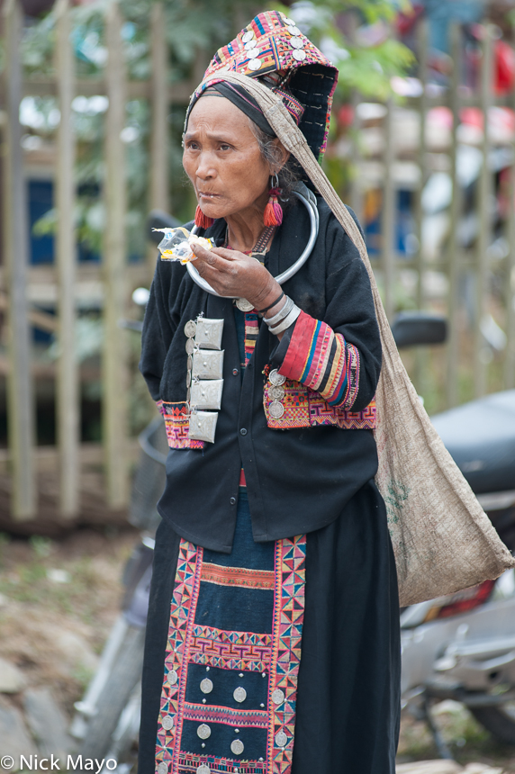 A traditionally dressed Pala woman snacking at Paknamnoy market.