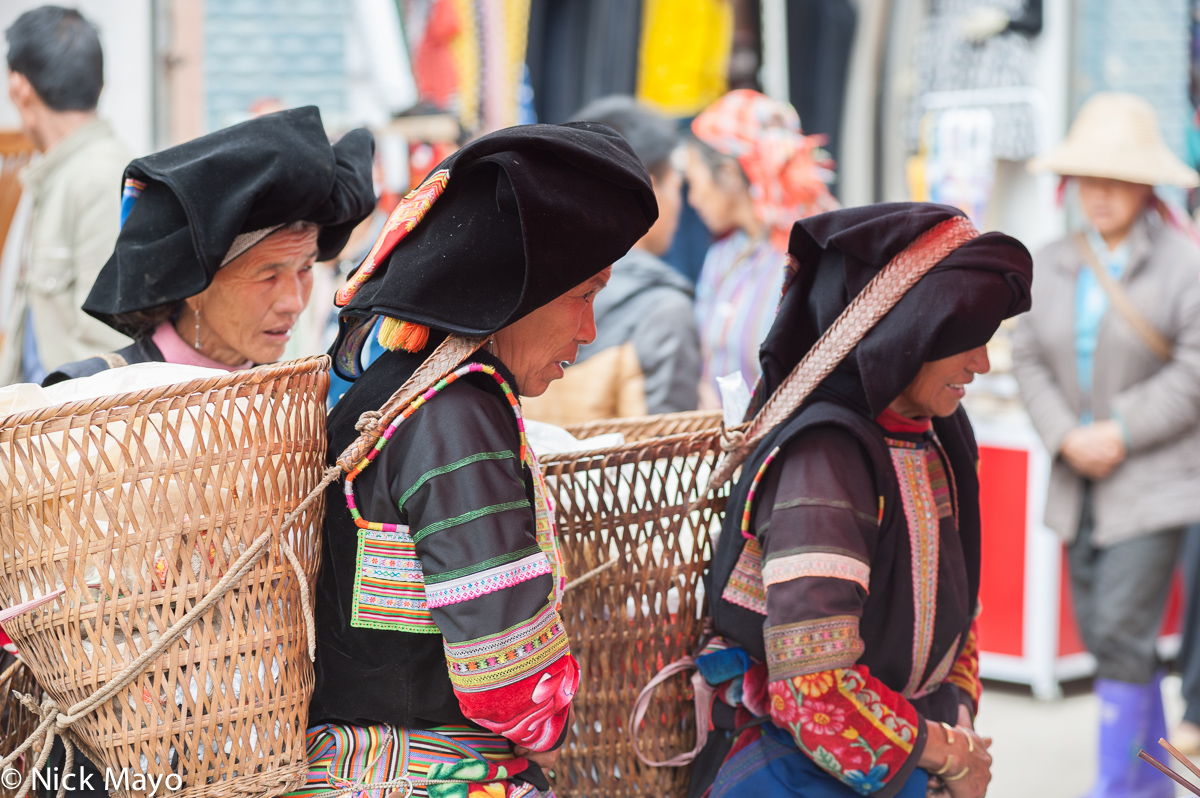 Three traditionally dressed Alu Yi women carrying baskets for their shopping expedition to Jemin market.