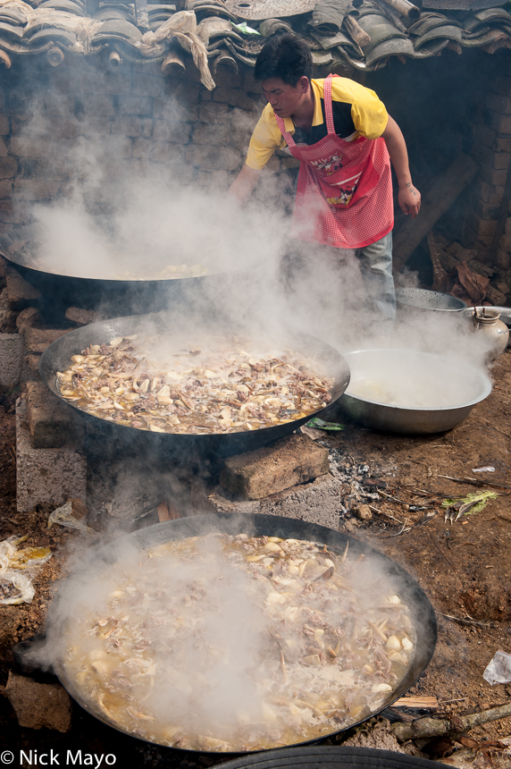 Meat being cooked in large woks for a wedding banquet in the Hani village of Huatien.