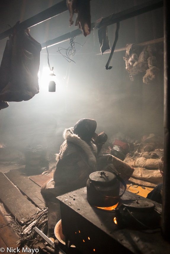 A Siberian Arctic Nenets woman boiling tea in a kettle on the chum stove at their camp on the Yamal peninsula.