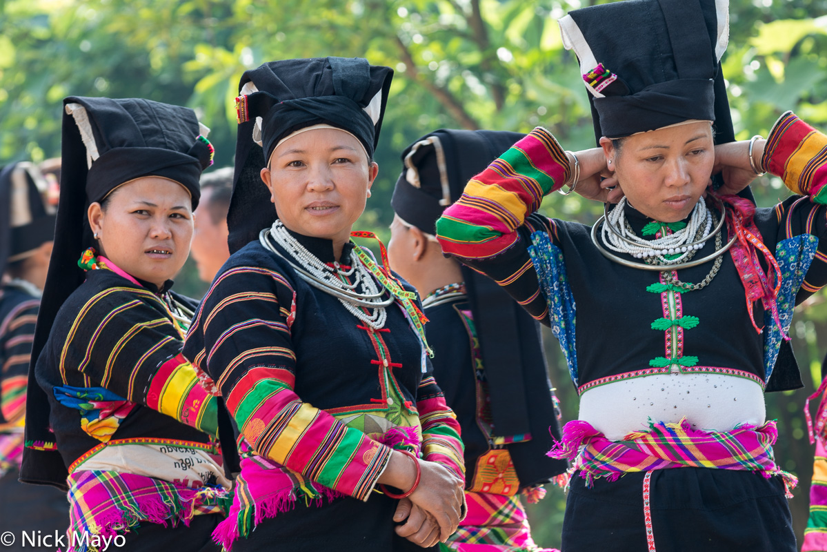 Red Yi women, wearing traditional clothes, hats and necklaces, at a festival in the village of Powu.