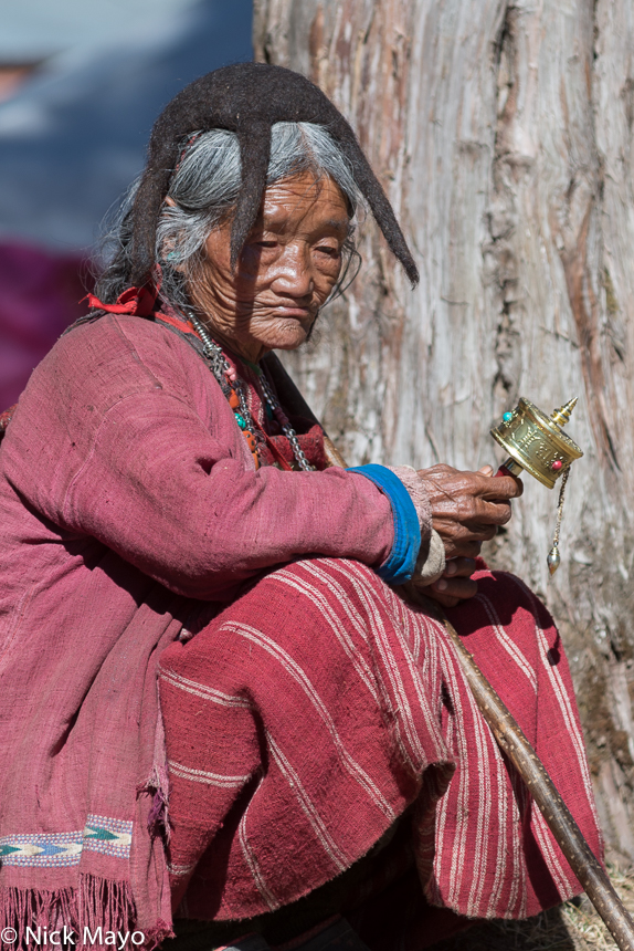 A Monpa woman wearing a traditional felted yak hair hat holds her prayer wheel during the Torgya festival at the Tawang monastery...