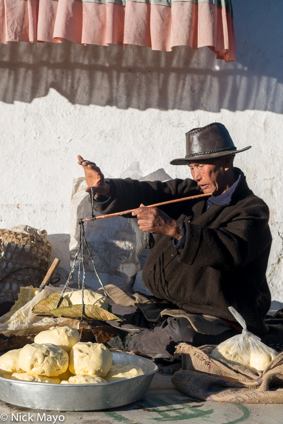 A visiting Dakpa trader weighing yak butter at the Torgya festival in the Tawang monastery.