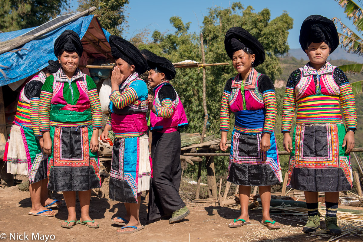 White Hmong women in their traditional clothes and peaked turbans waiting to be photographed in the village of Chen Jia Jie.