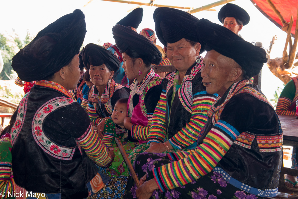 White Hmong women in their traditional peaked turbans chatting during a festival in the village of Ban Hong.