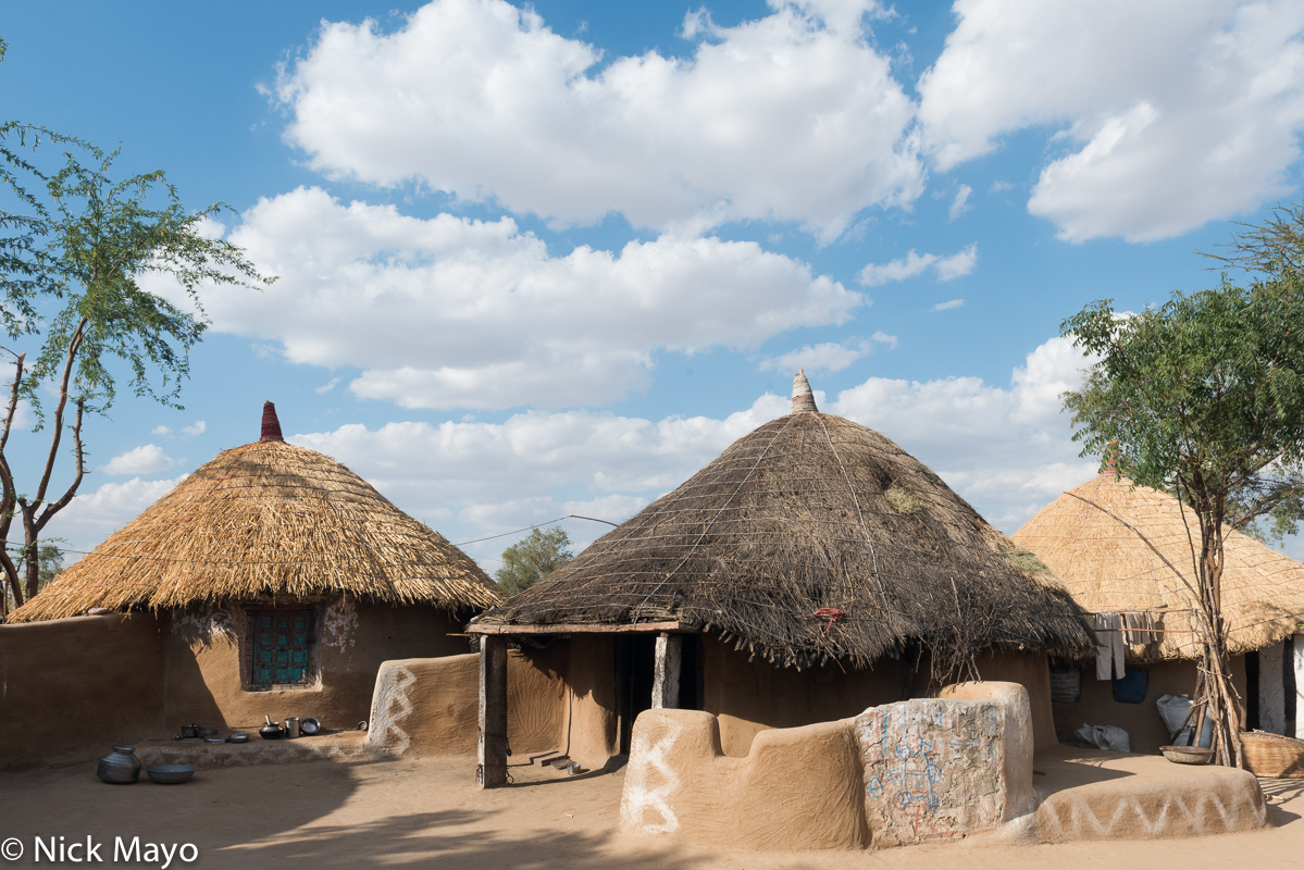 Three mud walled thatched bungas in the village of Kudi.