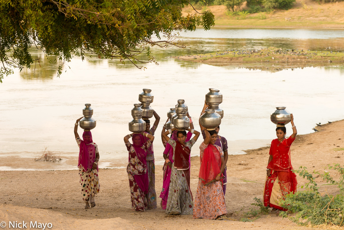 Women fetching water from the Sinli village pond at sunset.