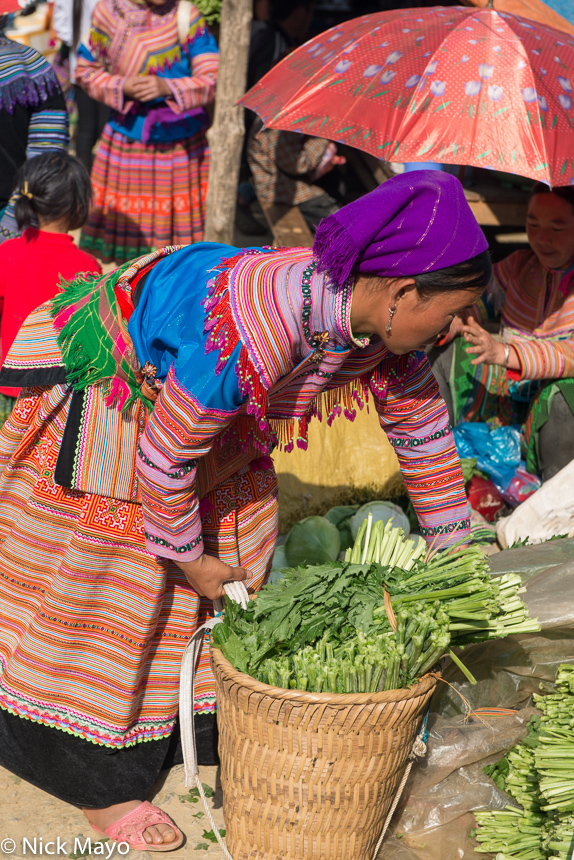 A Flowery Hmong woman with her basket of vegetables at Si Ma Cai market.