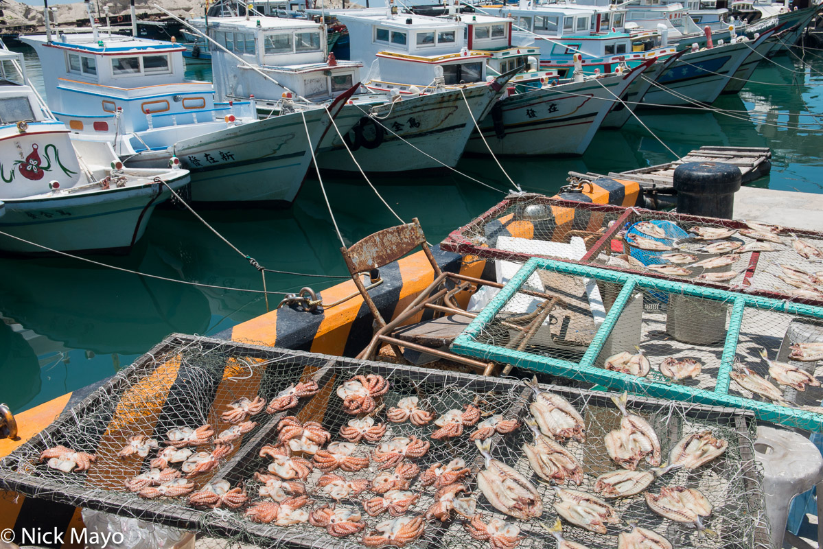 Fishing boats and drying octopuses and fish catch at Niaoyu island.