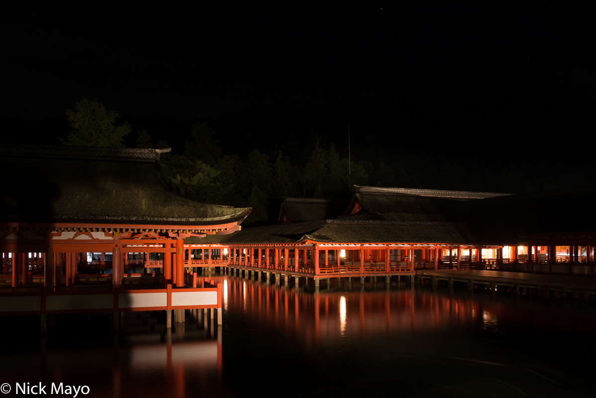 Night view of the Itsukushima temple on Miyajima with its thatched roofs.