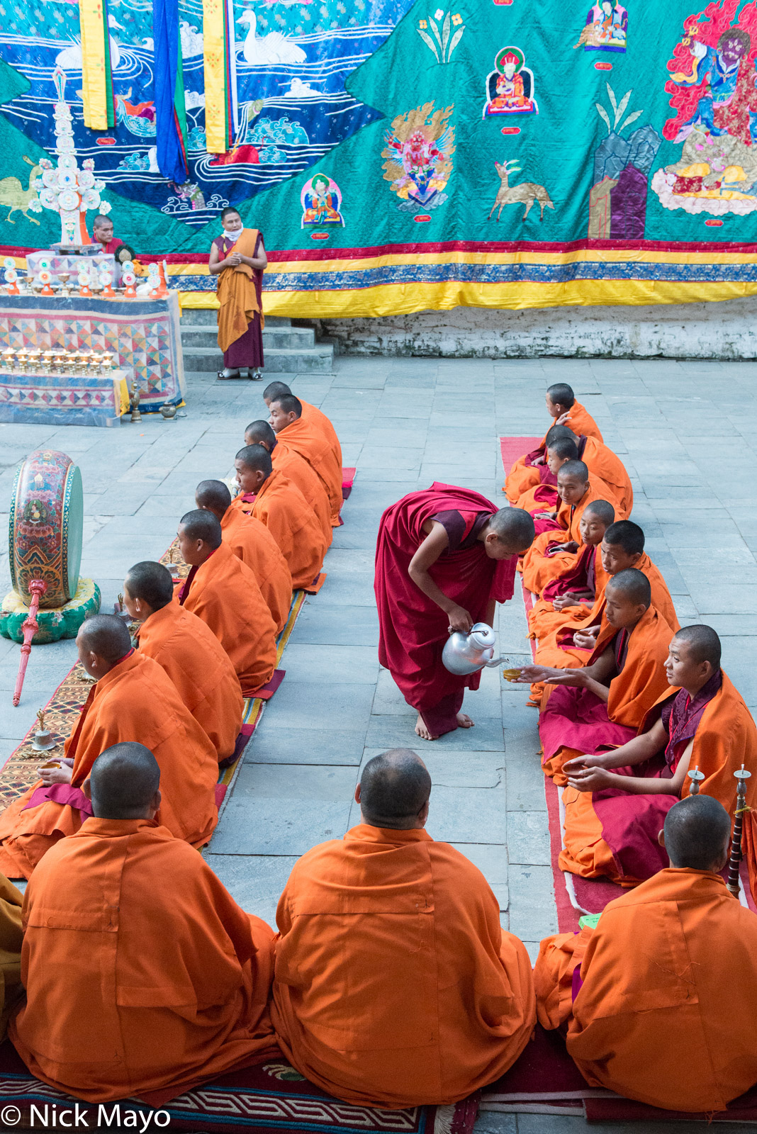 Monks receiving a ritual drink during a ceremony in front of the tanka and drum on the last day of the Mongar tshechu.