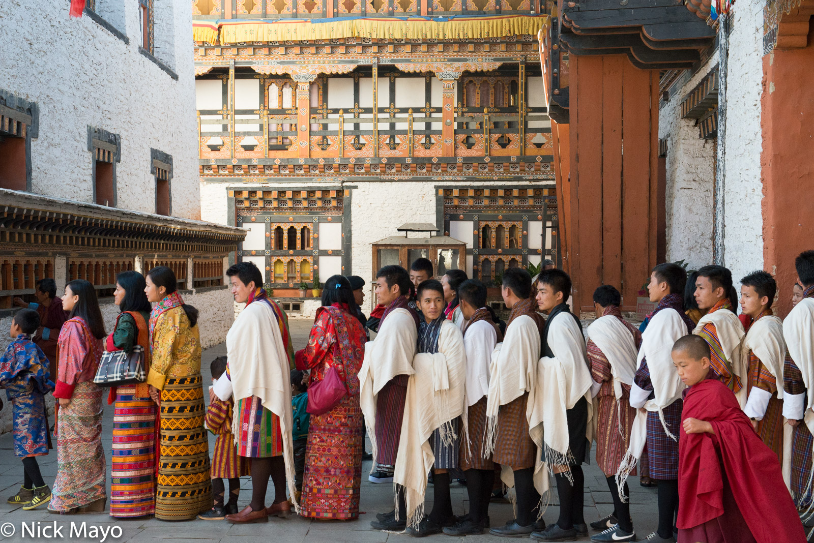 Men wearing white shawls waiting to seek blessings during the tshechu at Mongar dzong.