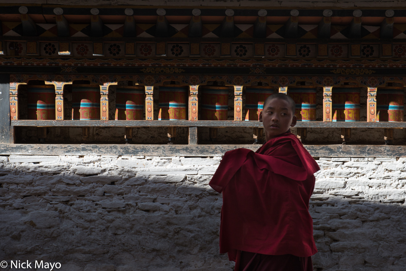 A young monk passing the prayer wheels at Mongar dzong during the annual tshechu.