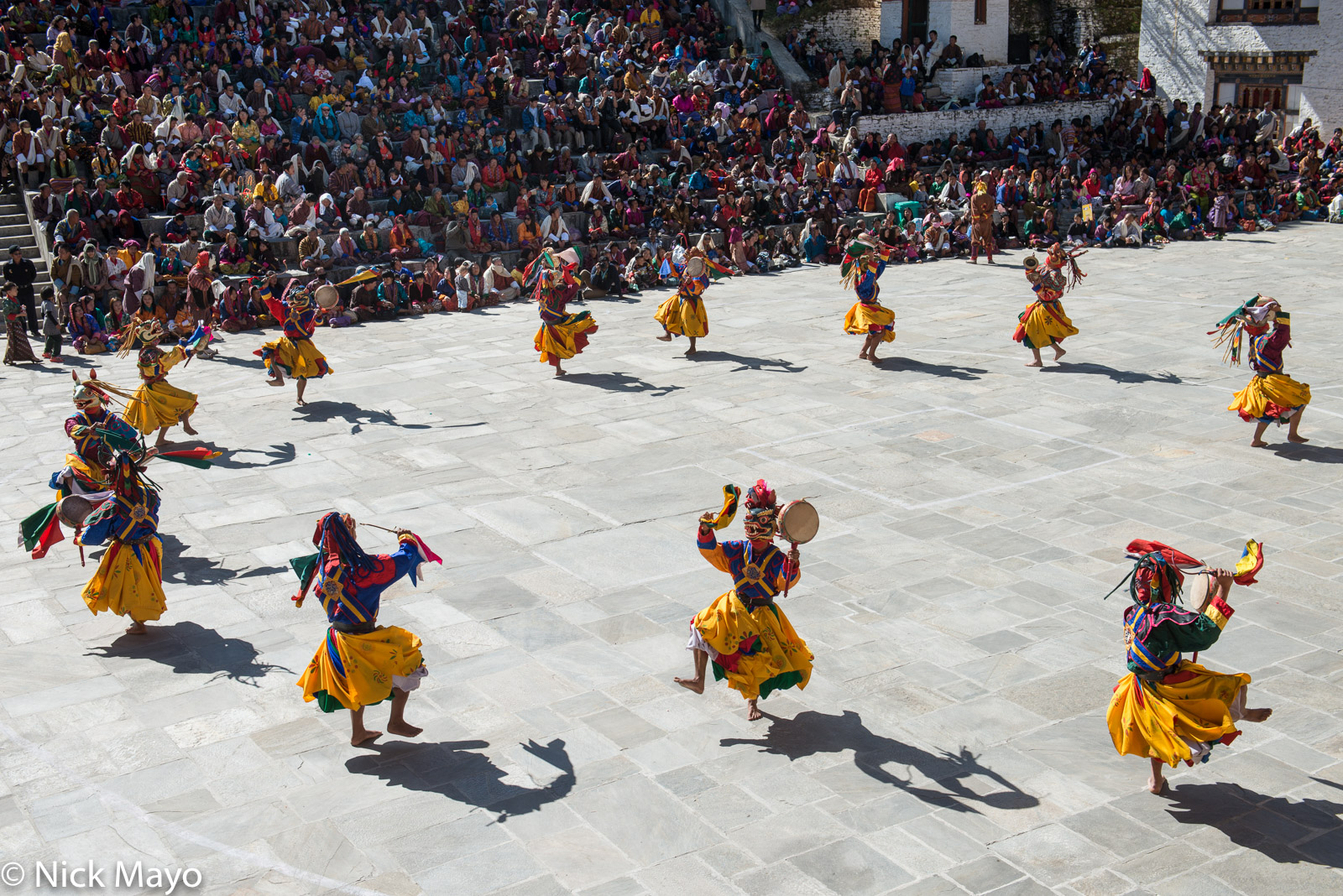 Masked monks holding hand drums while dancing at the tshechu at Mongar.