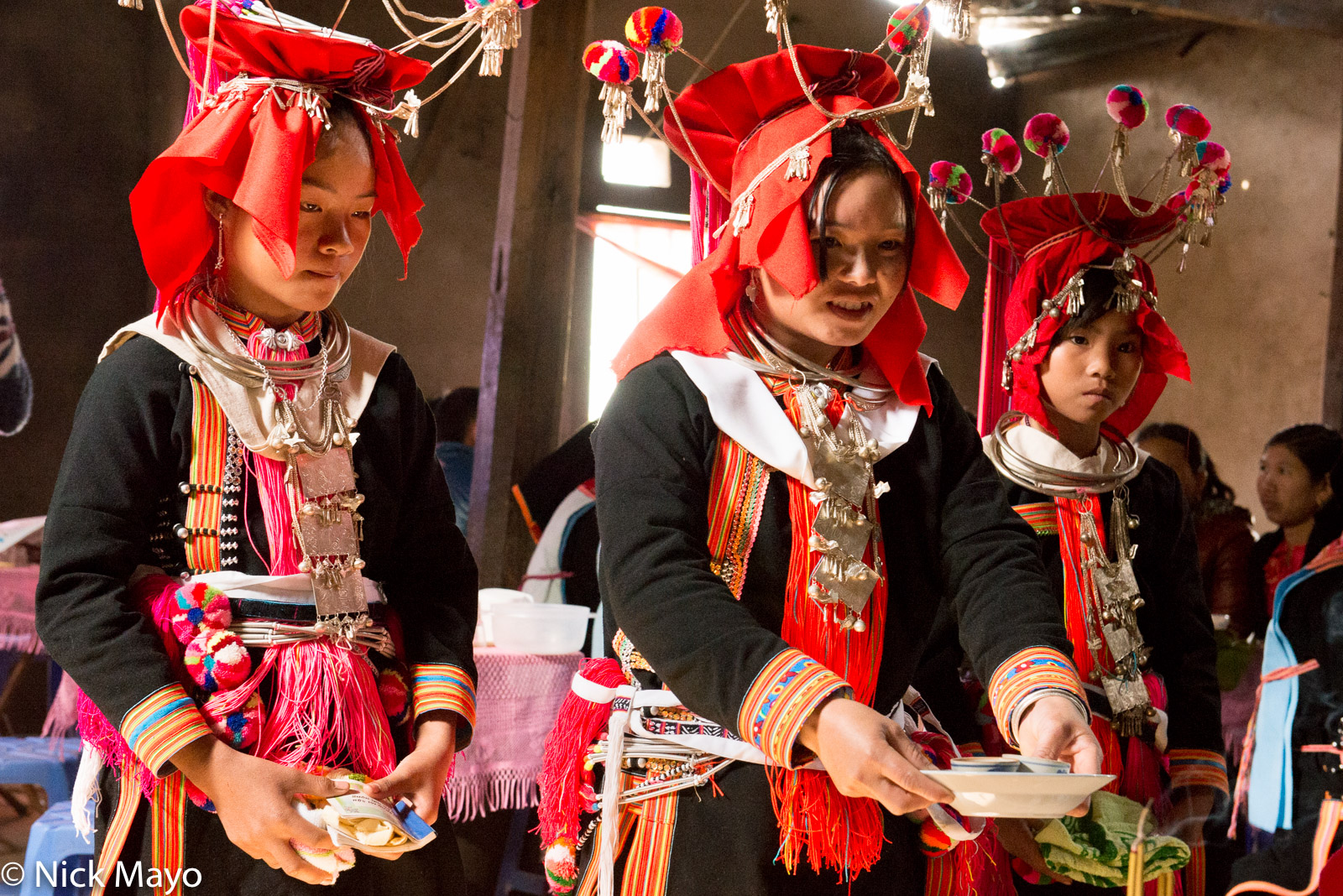 A Black Dao (Yao) bridesmaid offering drinks to the groom's father at a wedding in Ban Then Sin.