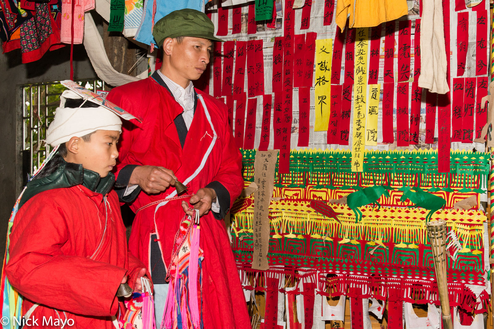 The initiate and his priest (sai mienh) father ringing handbells before the altar at a Dao (Yao) Le Cap Sac (coming of age) ceremony...