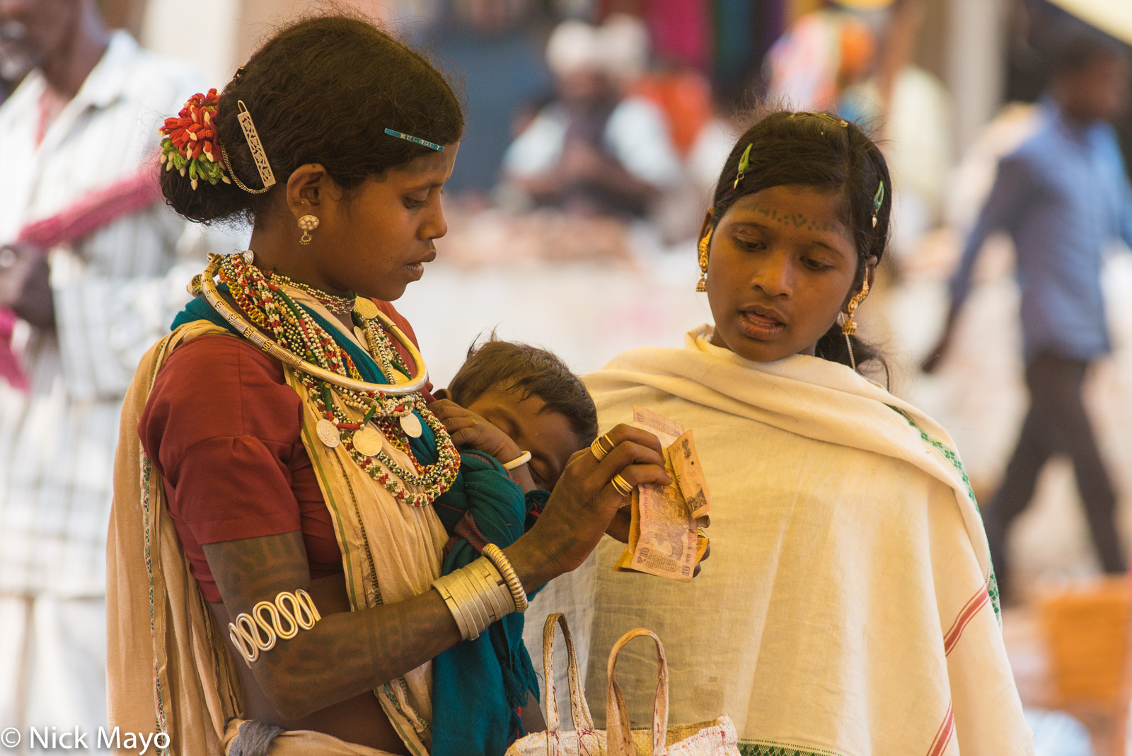 Tattooed Gond girls, wearing earrings, necklaces and bracelets, shopping at Taragaon market.