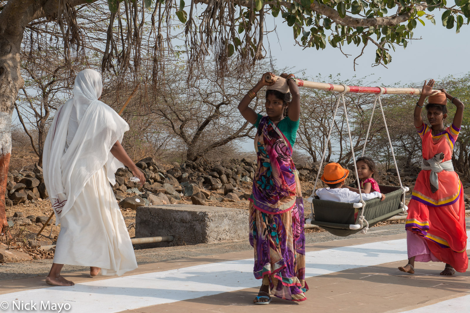 A Jain nun passing two children being carried in a litter basket on Shatrunjaya Hill at Palitana.