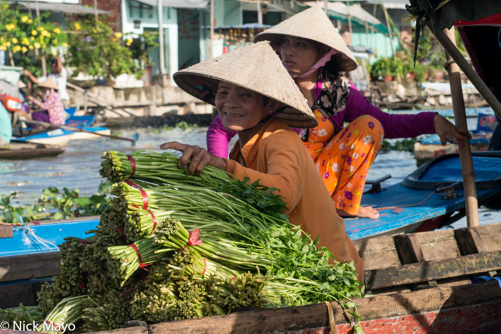 Two ladies in conical hats sorting vegetables at the floating market at Nga Nam in the Mekong Delta.