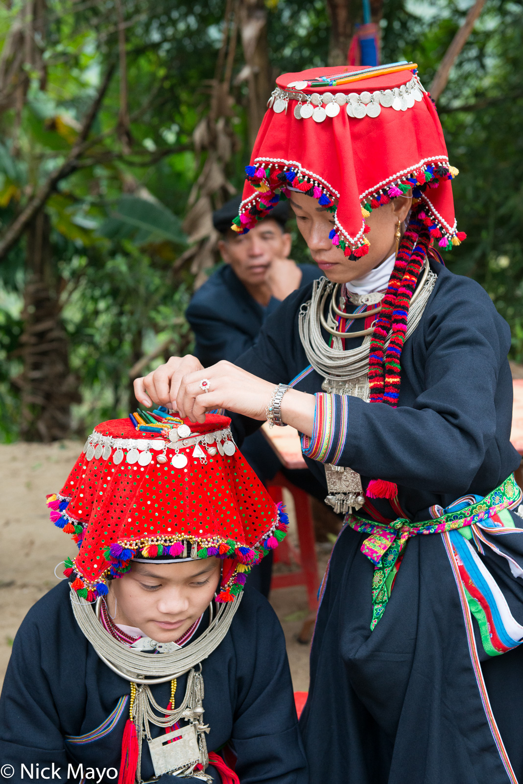 A Dao Ao Dai girl adjusting her sister's headwear during a wedding at Nam Dich.