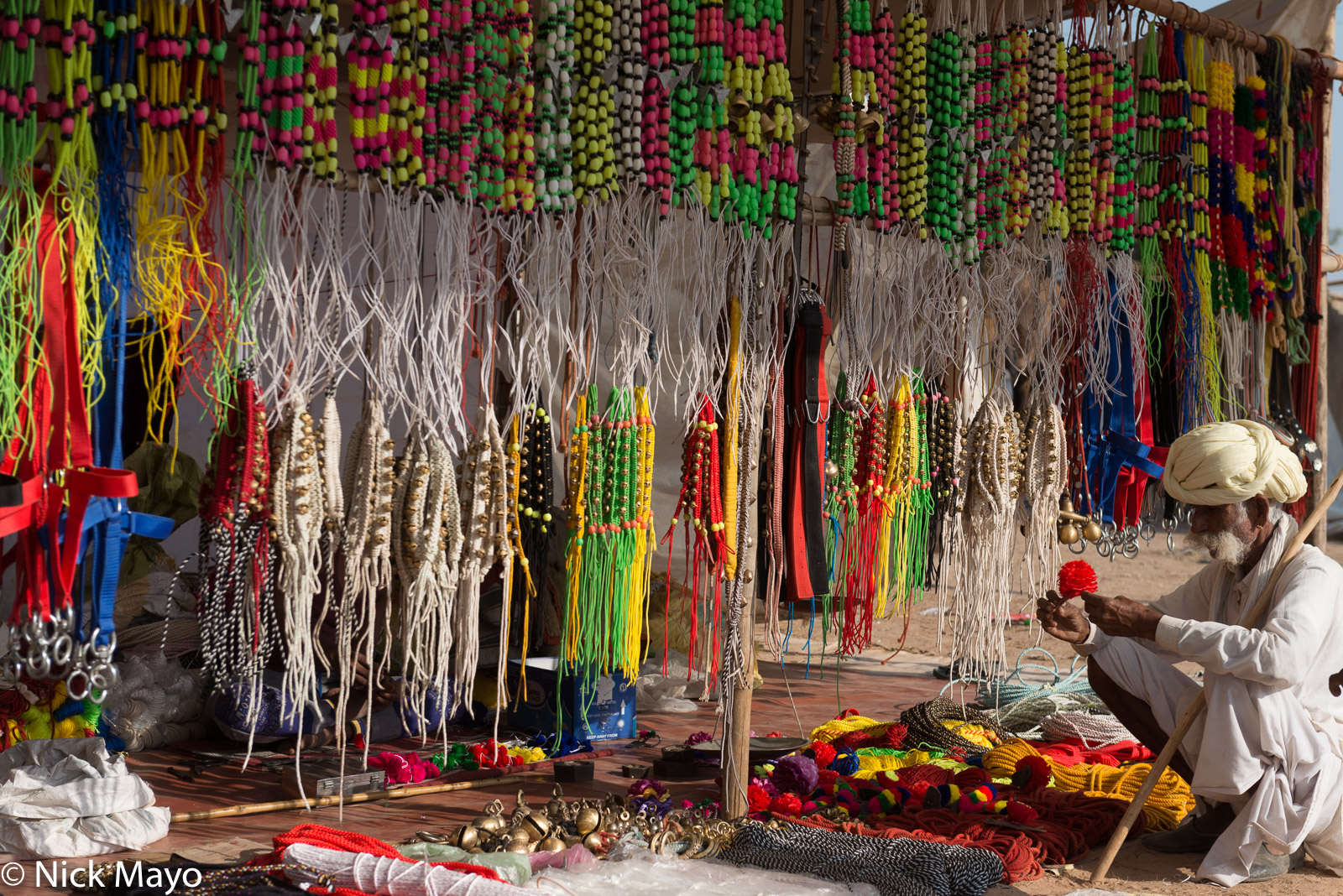 A camel owner examining decorations for animals on sale at the Nagaur cattle fair.